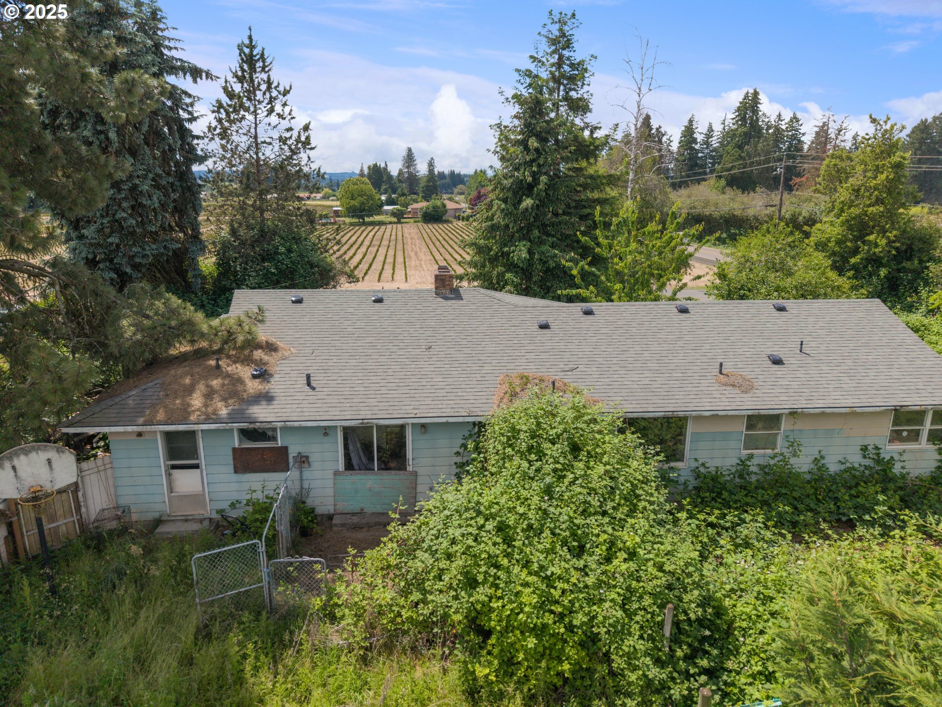 an aerial view of a house with yard and trees in the background