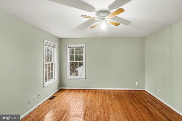 a view of an empty room with window and chandelier fan