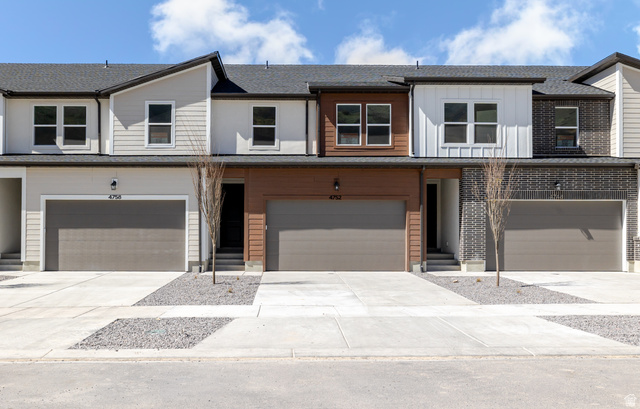 View of front facade featuring driveway, an attached garage, board and batten siding, and roof with shingles