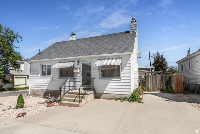 59 East Pinehurst Street Tooele, UT 84074 - Photo 1 of 22 White siding exterior featuring a dark shingle roof, concrete driveway, and striped window awnings