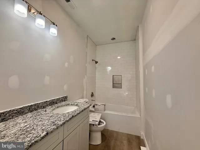 a bathroom with a granite countertop sink a toilet and shower