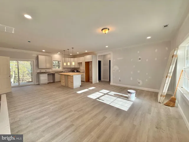 a open kitchen with kitchen island a stove a refrigerator a sink dishwasher and a dining table with wooden floor