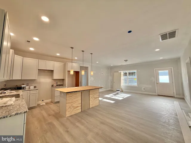 a view of kitchen with kitchen island wooden floors appliances and cabinets