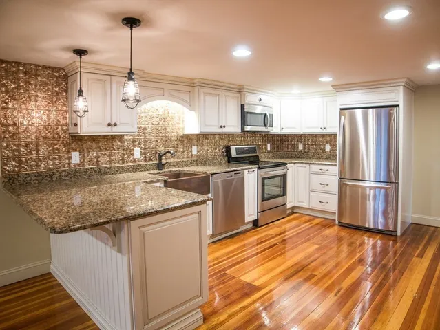 a kitchen with stainless steel appliances granite countertop a sink a stove and a refrigerator