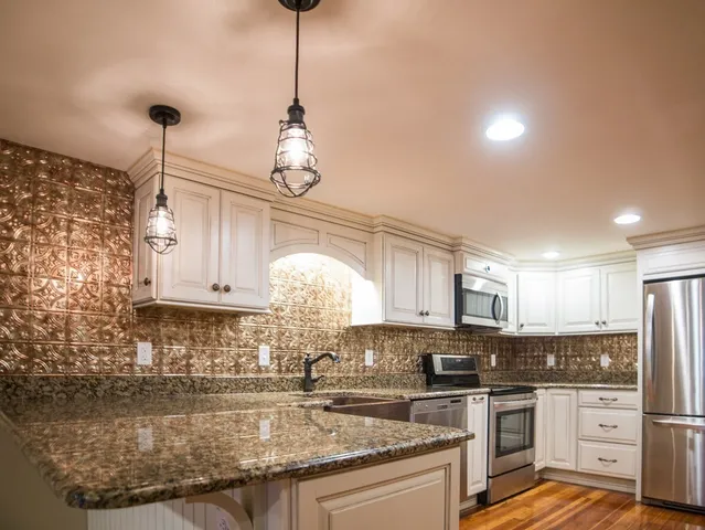 a kitchen with stainless steel appliances granite countertop a sink a stove and cabinets