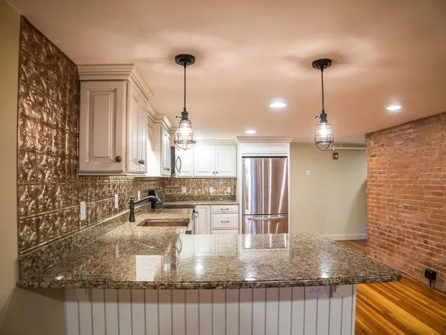 a kitchen with kitchen island granite countertop a sink a counter top space and cabinets