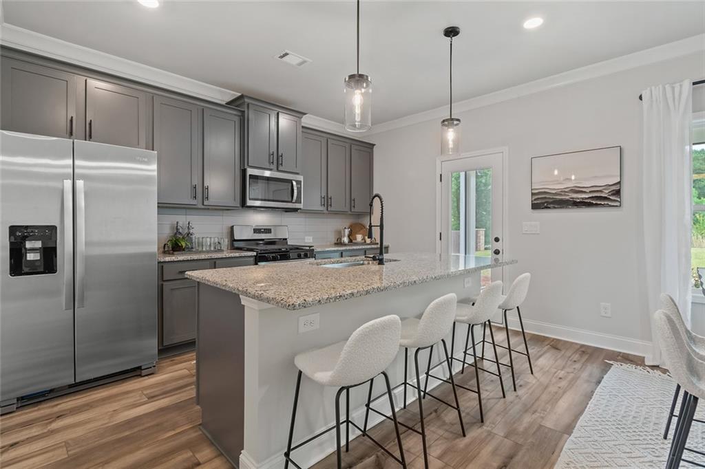 73 Cardinal Pond Lane Winder, GA 30680 - Photo 13 of 59 a kitchen with stainless steel appliances granite countertop a stove a refrigerator a kitchen island a dining table and chairs