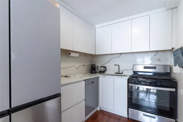 a kitchen with granite countertop white cabinets and stainless steel appliances