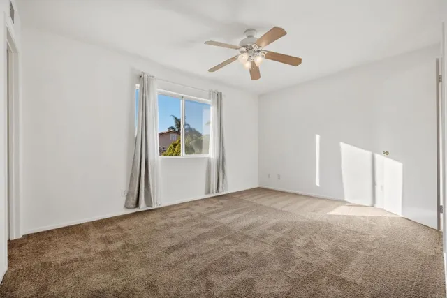 a view of a big room with wooden floor and chandelier fan