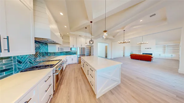 a large kitchen with kitchen island a sink a counter top space stainless steel appliances and cabinets