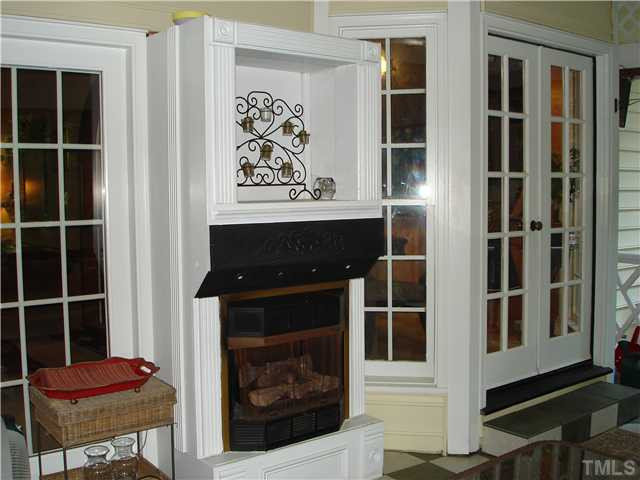 5505 North Hawthorne Way Raleigh, NC 27613 - Photo 7 of 12 Screened porch has built in niche for TV, fireplace, space for table and chairs, seating, gas grill hookup, tile floor, beadboard ceiling and ceiling fan. Door leads to custom deck; backs up to woods and walking trails. Screened Porch
