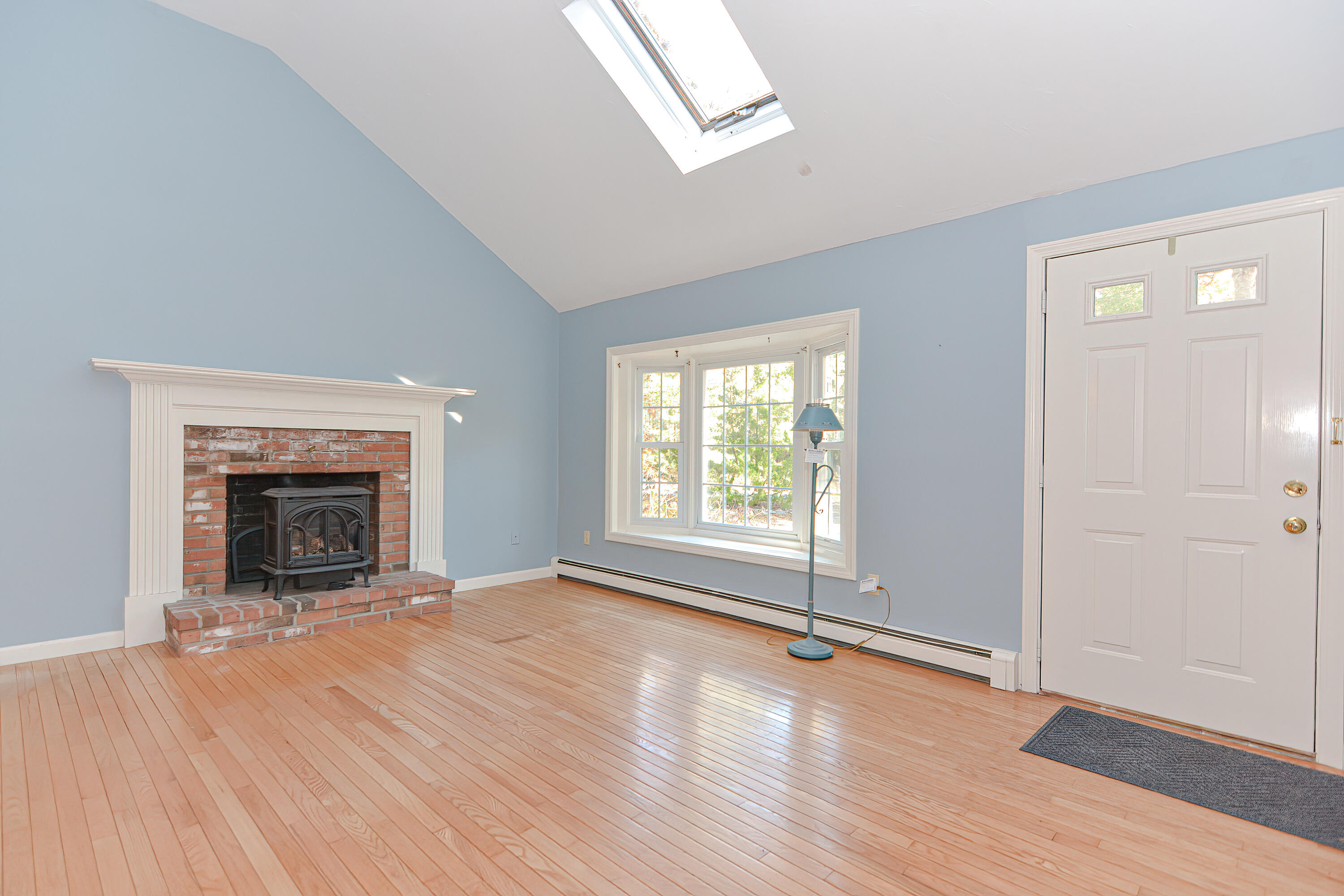 235 Simon Narrows Road Mashpee, MA 02649 - Photo 8 of 30 an empty room with wooden floor fireplace and windows