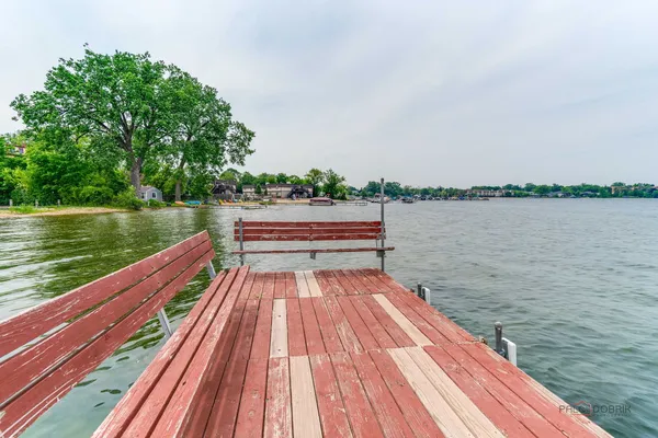 a view of wooden deck and lake with trees in the background