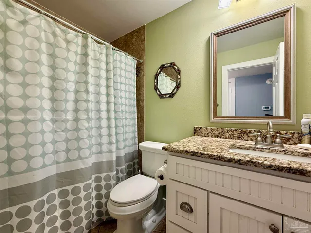 a bathroom with a granite countertop toilet sink and mirror