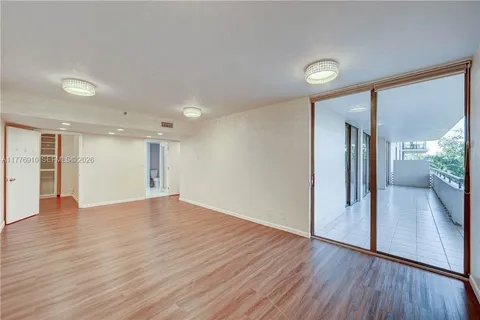 a view of empty room with wooden floor and a window