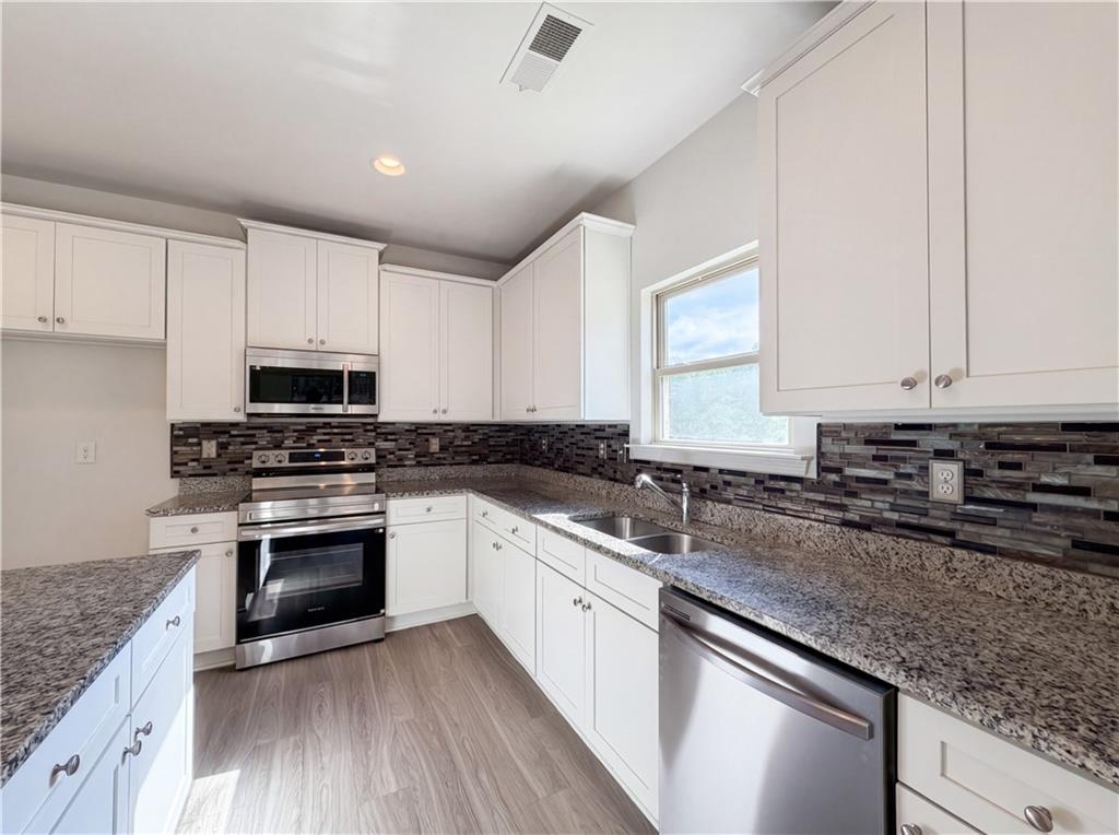 4075 McClendon Way Rex, GA 30273 - Photo 7 of 25 a kitchen with stainless steel appliances granite countertop a sink stove and cabinets