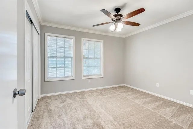 an empty room with chandelier fan and windows