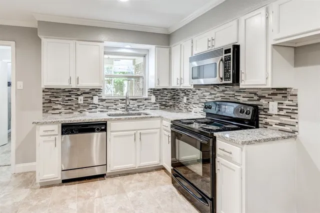 a kitchen with granite countertop a sink stove and cabinets