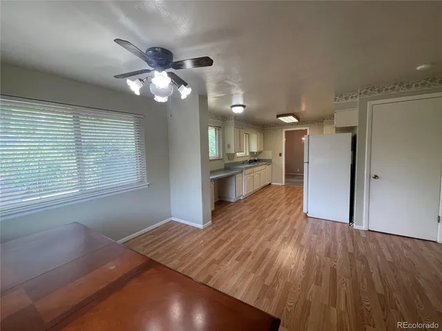 a view of a kitchen and an empty room with wooden floor and a kitchen