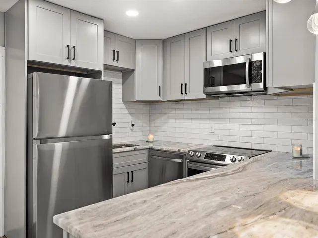 a kitchen with stainless steel appliances granite countertop a refrigerator sink and microwave