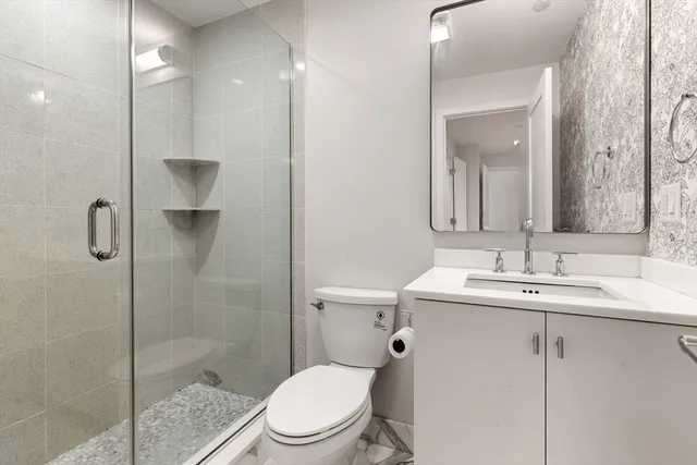 a bathroom with a toilet a sink a shower and mirror
