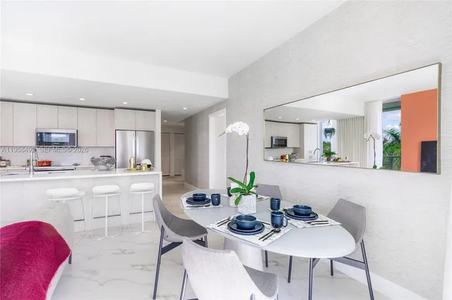 a kitchen with stainless steel appliances kitchen island granite countertop a dining table chairs and a refrigerator