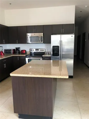 a kitchen with kitchen island sink and refrigerator