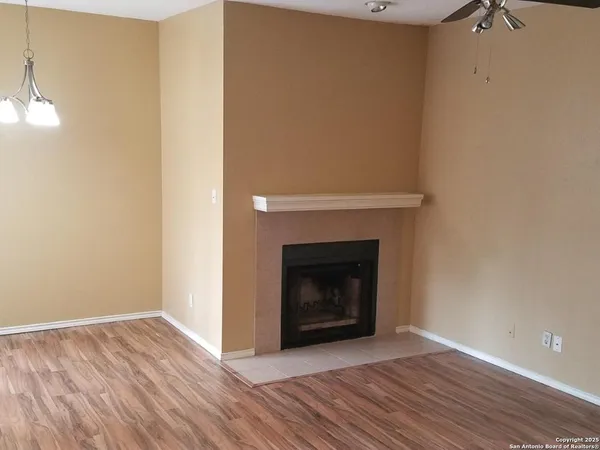 a view of an empty room with wooden floor and a fireplace