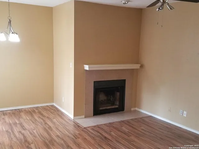 a view of an empty room with wooden floor and a fireplace