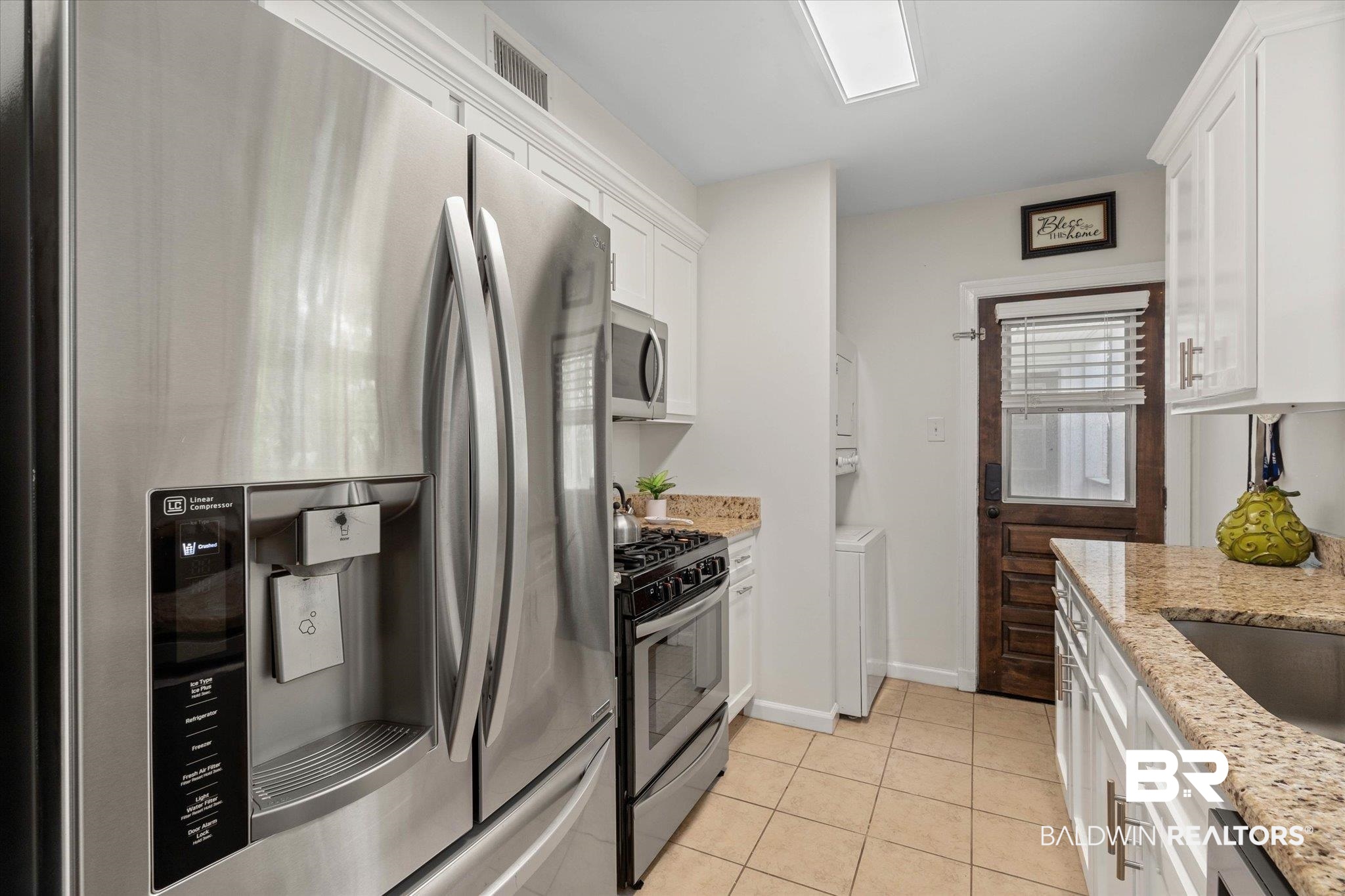 214 Upham Street, Unit 18A Mobile, AL 36607 - Photo 9 of 29 Kitchen with stainless steel appliances, white cabinets, light tile patterned floors, washer / clothes dryer, and light stone countertops