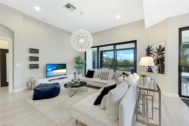 a living room with furniture a chandelier a large window and a chandelier