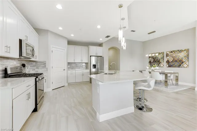a kitchen with kitchen island a stove a sink a refrigerator and cabinets