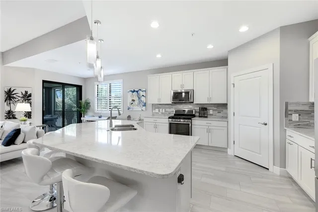 a large kitchen with kitchen island a stove a sink a refrigerator and white cabinets with wooden floor