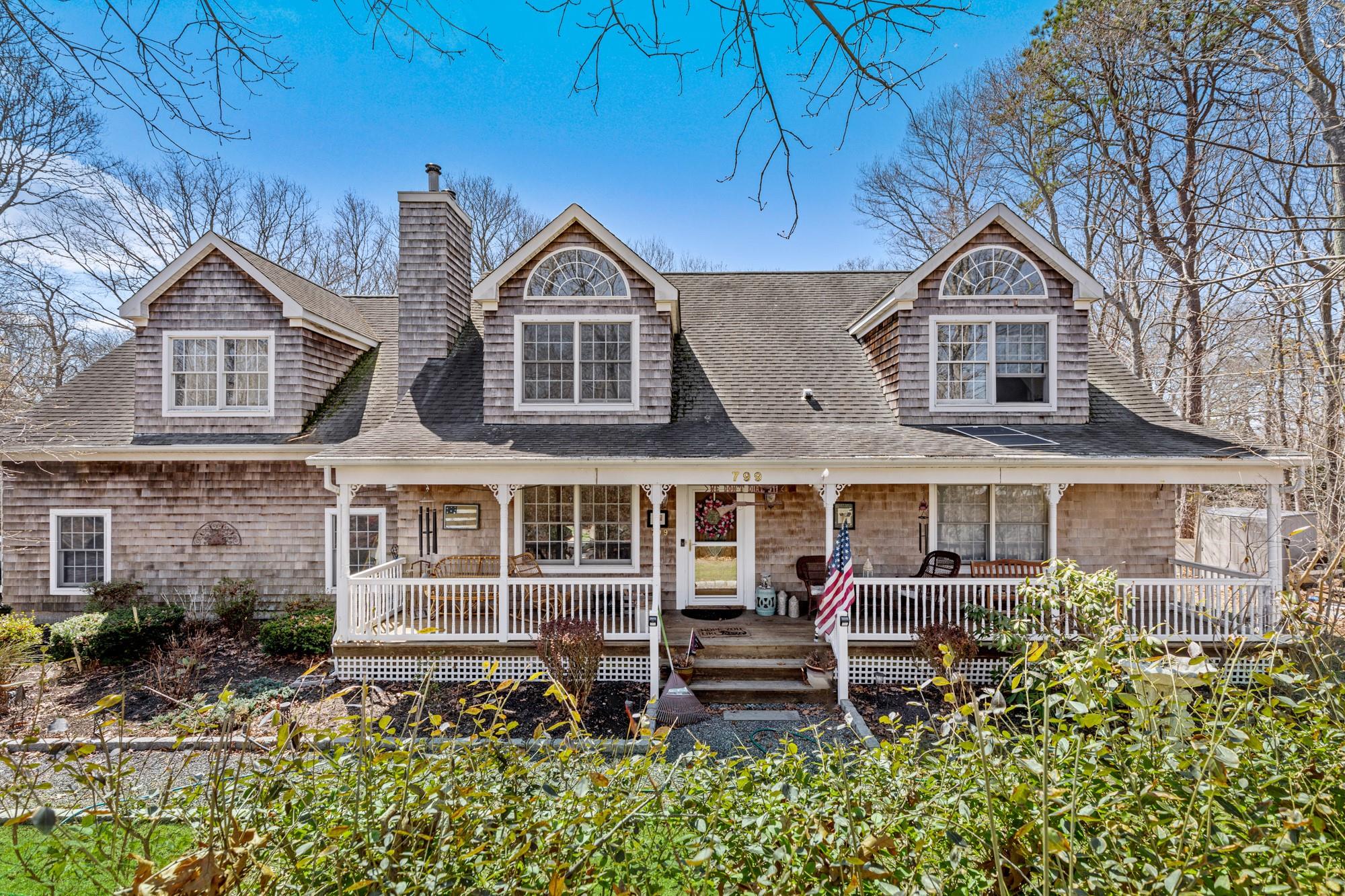 View of front facade featuring roof with shingles, a chimney, and covered porch