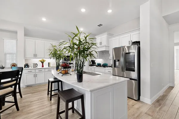a kitchen with stainless steel appliances a dining table chairs microwave and refrigerator
