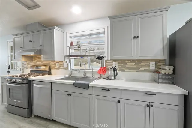 a kitchen with a sink white cabinets and white stainless steel appliances