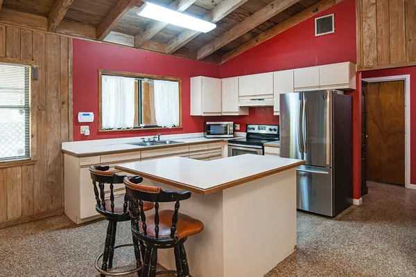 a kitchen with stainless steel appliances kitchen island a table chairs in it and wooden floors