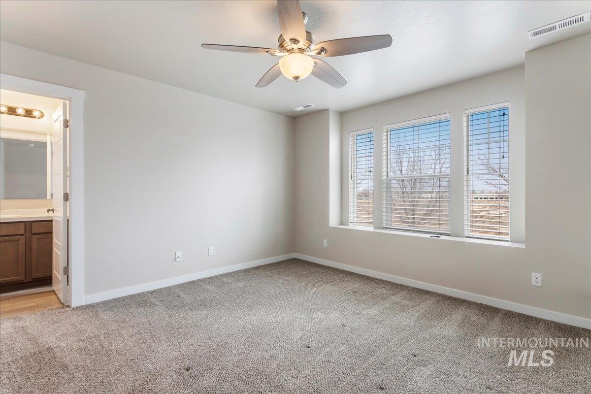 2501 East Goldstone Street Meridian, ID 83642 - Photo 13 of 26 Unfurnished bedroom featuring light colored carpet, a ceiling fan, and connected bathroom