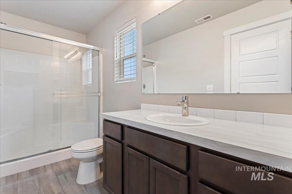 2501 East Goldstone Street Meridian, ID 83642 - Photo 17 of 26 Bathroom with vanity, a shower stall, and light wood-style flooring