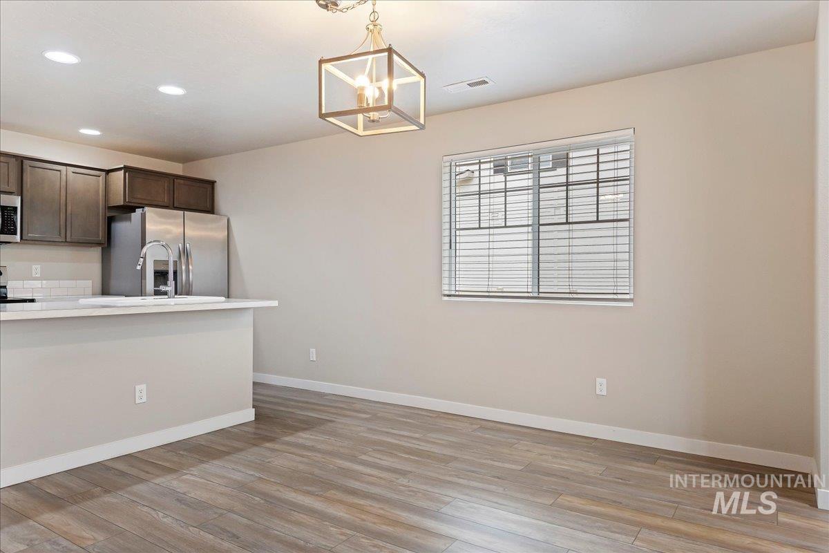 2501 East Goldstone Street Meridian, ID 83642 - Photo 8 of 26 Kitchen with dark wood finish cabinetry, stainless steel appliances, light wood-style flooring, and hanging lights