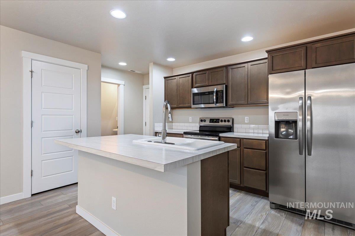 2501 East Goldstone Street Meridian, ID 83642 - Photo 9 of 26 Kitchen featuring stainless steel appliances, light countertops, light wood-style flooring, dark wood finish cabinets, and recessed lighting