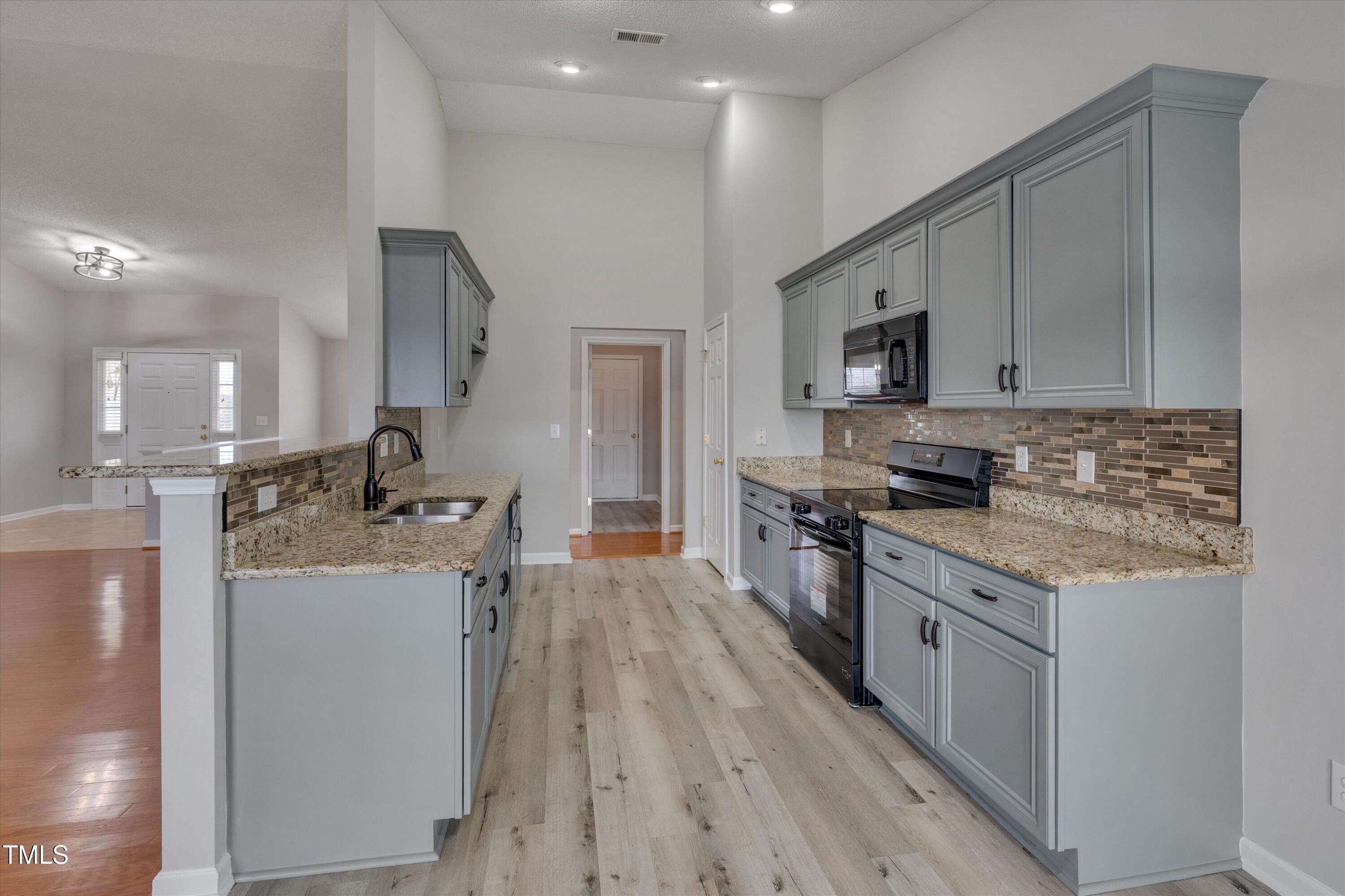 3217 Flowery Branch Road Raleigh, NC 27610 - Photo 4 of 12 a kitchen with stainless steel appliances granite countertop a stove top oven a sink dishwasher and a refrigerator