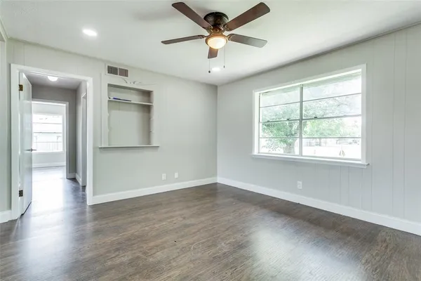 a view of an empty room with a window and wooden floor