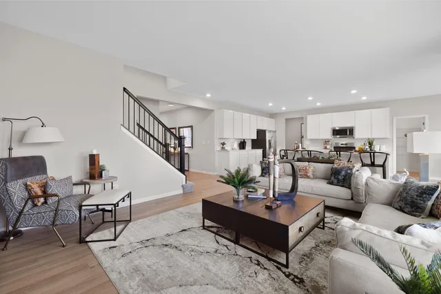 a living room with furniture kitchen view and a wooden floor