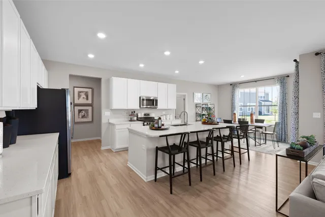 a kitchen with stainless steel appliances a dining table chairs stove refrigerator and cabinets