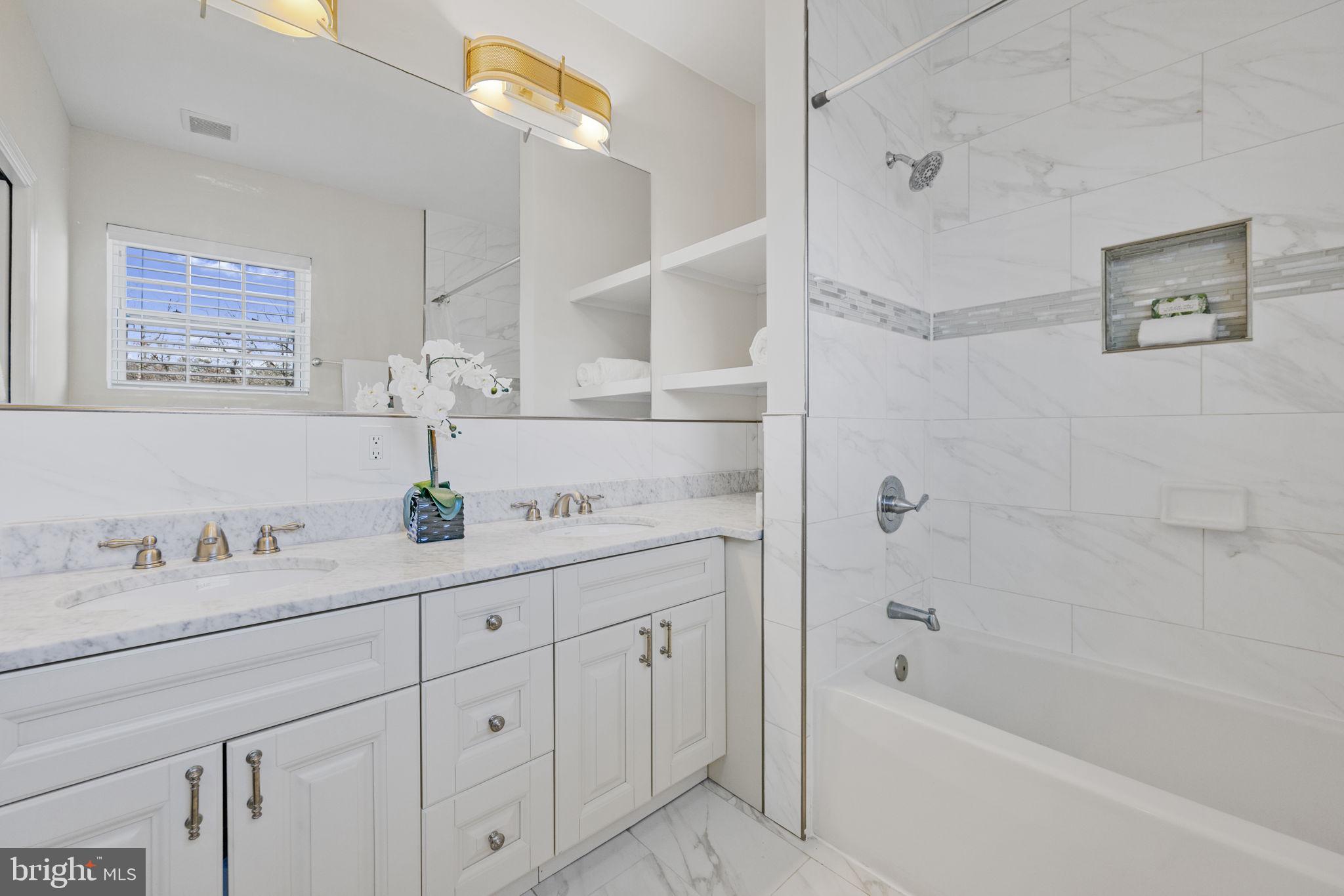 2420 West Rogers Avenue Baltimore, MD 21209 - Photo 29 of 67 a bathroom with a granite countertop sink a mirror a bathtub and shower