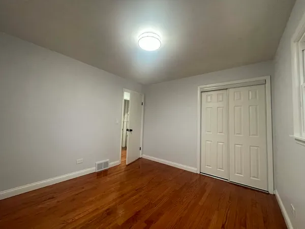 a view of a hallway with wooden floor and closet