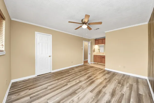 a view of empty room with wooden floor and fan