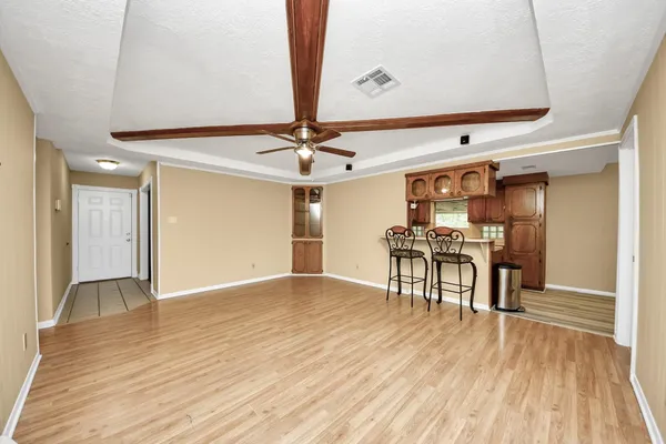 a view of a room with wooden floor a ceiling fan and kitchen space