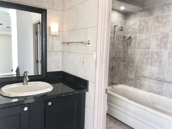 a bathroom with a granite countertop sink and a bathtub